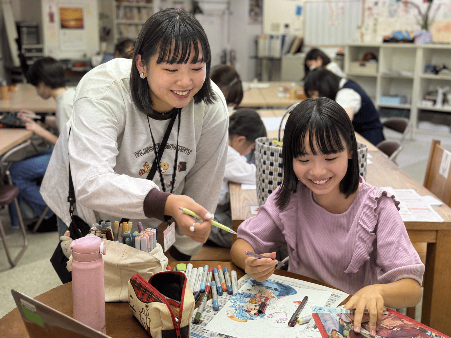 作品を見ながら講師のアドバイスを聞く生徒
