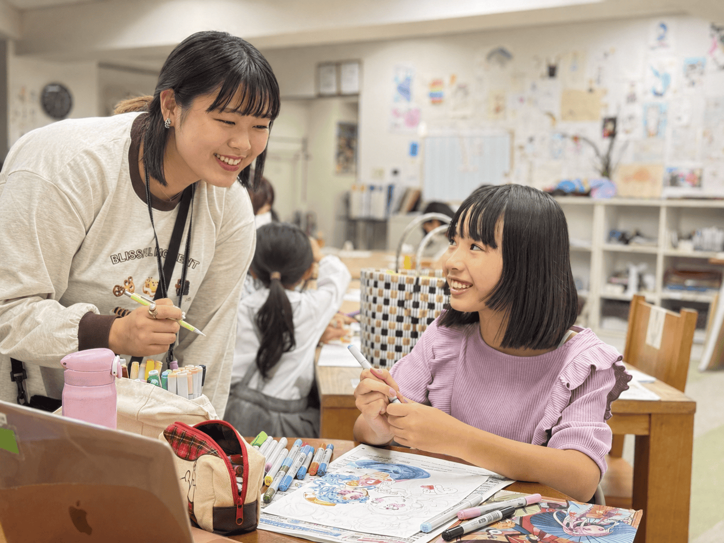 描きかけの作品について笑顔で話す講師と生徒