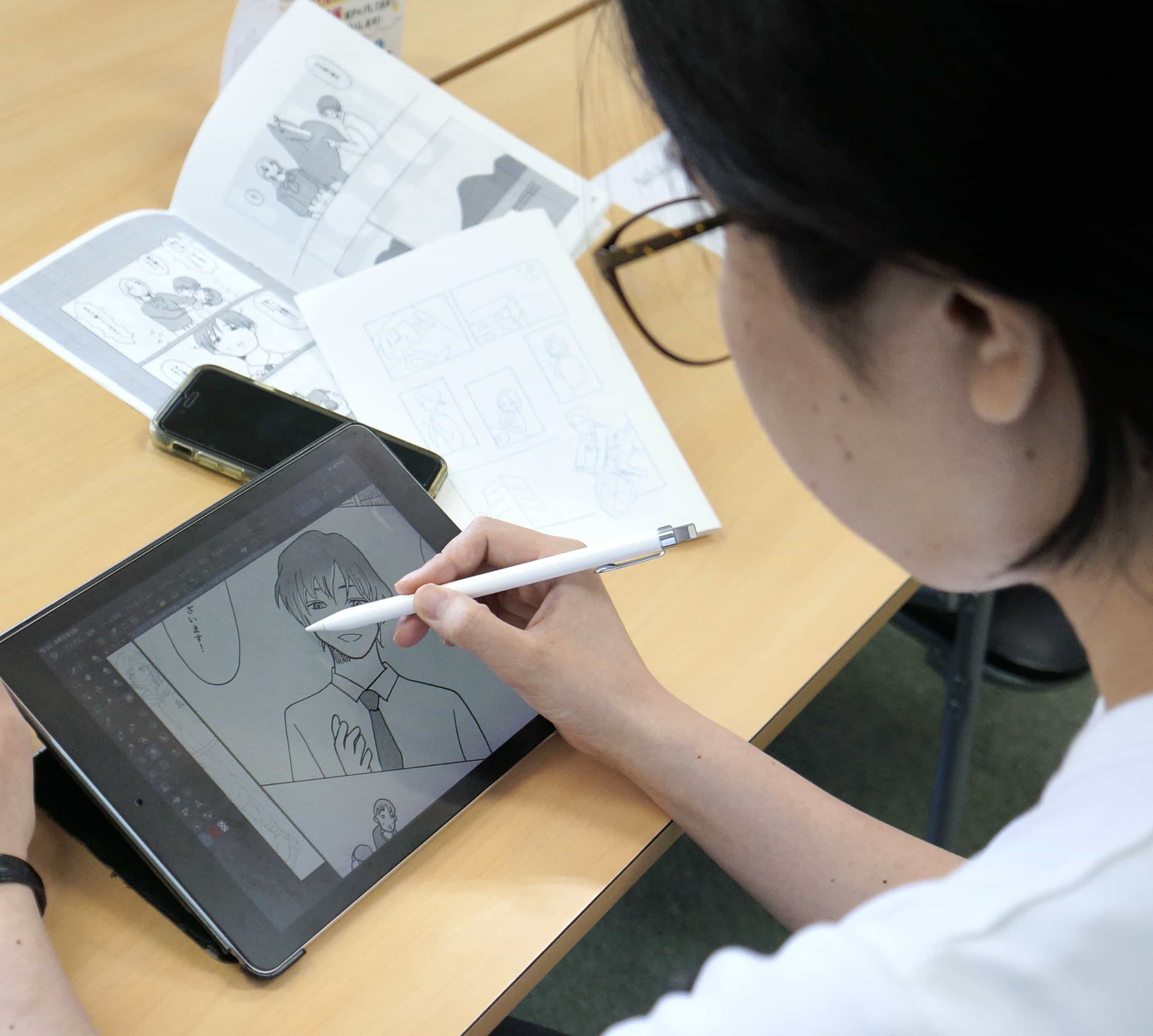原稿用紙にペンでマンガを描く受講生
