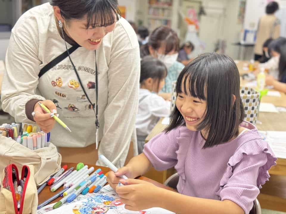 子どもたちがテーブルで制作する教室と、見て回る講師